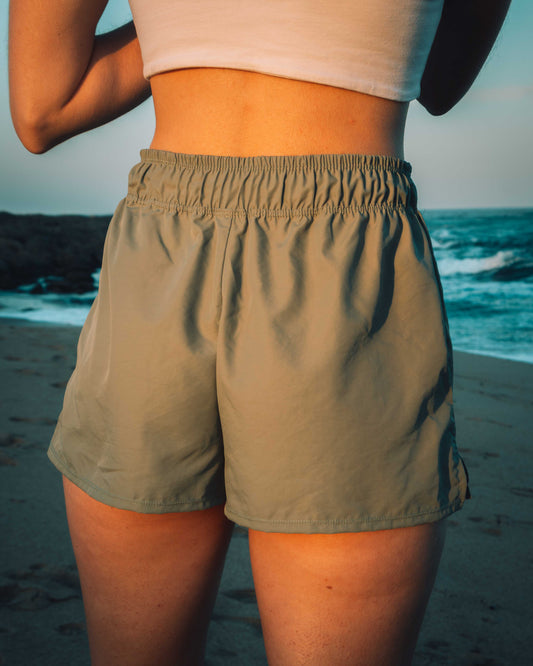 Person wearing khaki shorts on a beach with ocean view