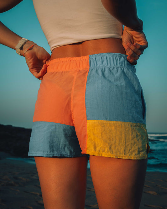 Person wearing a color-blocked pair pf shorts on a beach with ocean view