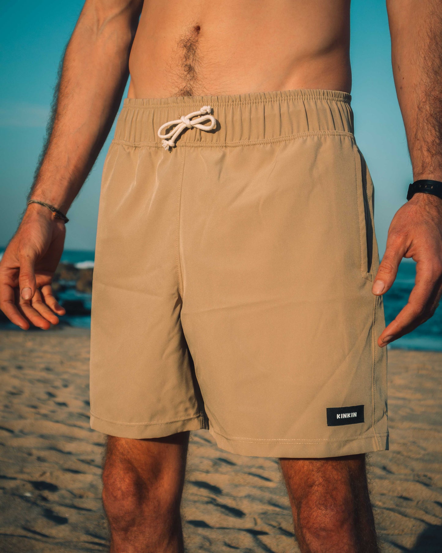 Beige swim shorts worn by a person on a beach