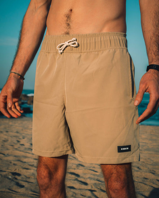 Beige swim shorts worn by a person on a beach