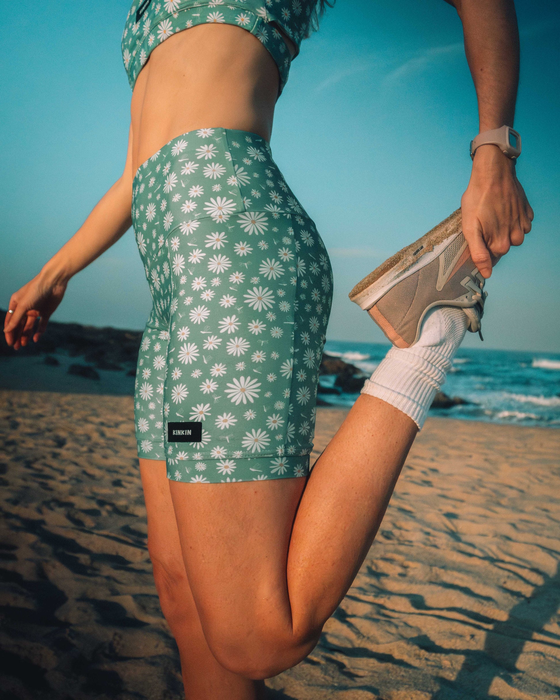 Person wearing green floral shorts on a beach